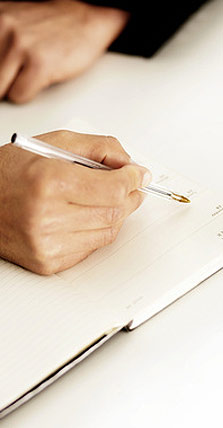 Hände beim Schreiben in ein Notizbuch
